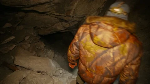 A man in the dark with a flashlight climbs into a dark cave. Stock Footage 86076672