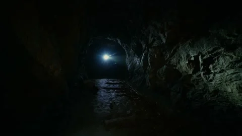 A man in the dark with a flashlight walking along an abandoned tunnel Stock Footage 86075153
