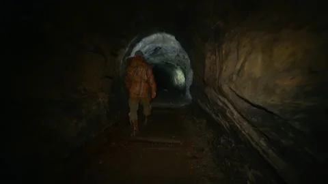 A man in the dark with a flashlight walking along an abandoned mine Stock Footage 86075409