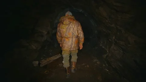 A man in the dark with a flashlight walking along an abandoned mine Stock Footage 86075518