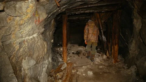 A man in the dark with a flashlight is walking along an abandoned mine with wood Stock Footage 86075974