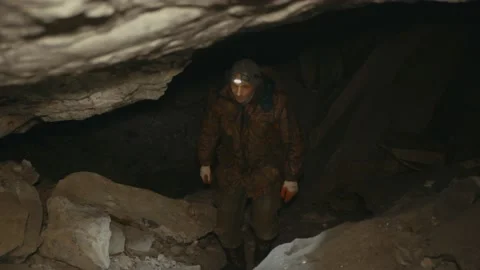 A man in the dark with a flashlight walking along a dark cave. Stock Footage 86077228