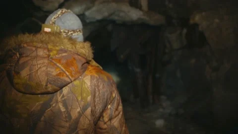 A man in the dark with a flashlight walks through an abandoned mine Stock Footage 86075719