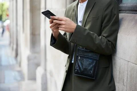 Man in dark green suit using smartphone, mid section Stock Photos