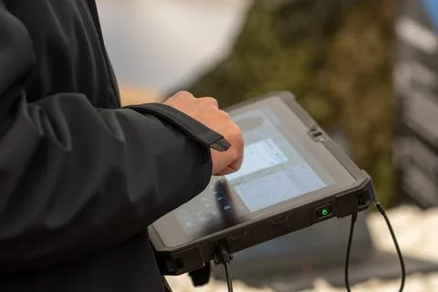 A man in a dark jacket uses a secure tablet to control military systems. Stock Photos