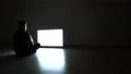 The man in the dark room sitting on the floor near the television 4k or 4k+ Resolution
