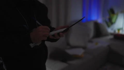 A man in a dark room taking notes with a tablet, suggesting a modern detect.. Video stock 279389003