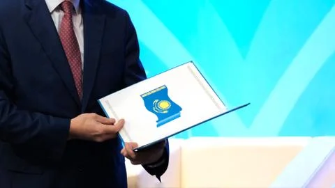 A man in a dark suit holds a folder with the image of the national flag of th Stock Photos