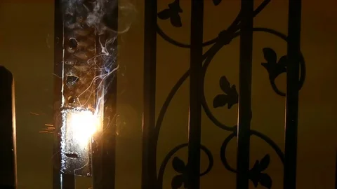 A man In the dark welds a lock in a wrought-iron gate Stock Footage 73856635