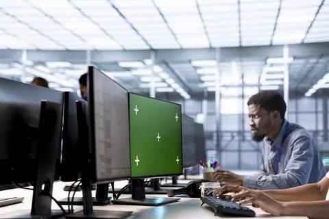 Man in data center updating systems on green screen PC to protect servers Stock Photos