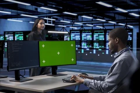 Man in data center updating systems on green screen PC to protect servers Stock Photos