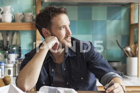 Man Daydreaming In Messy Kitchen