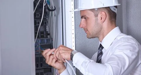 Man dealing with wires in a modern datacenter server room Stock Photos