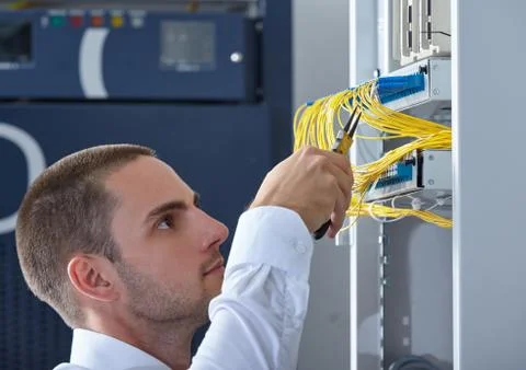 Man dealing with wires in a modern datacenter server room Stock Photos