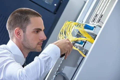 Man dealing with wires in a modern datacenter server room Stock Photos