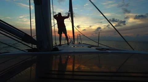 Man on deck of sailing yacht at beautiful sunset. Stock Footage