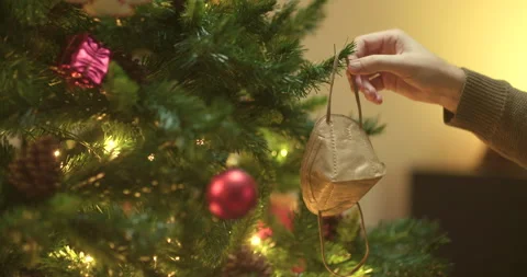Man decorates christmas tree with face mask Stock Footage 143852545