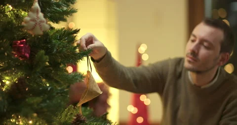 Man decorates christmas tree with face mask Stock Footage 143852546