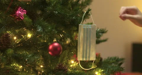 Man decorates christmas tree with face mask Stock Footage 143853182