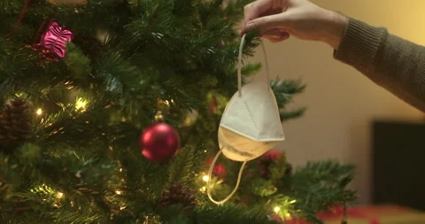 Man decorates christmas tree with face mask Stock Footage 143853393