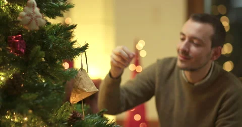 Man decorates christmas tree with face mask Stock Footage 143854218