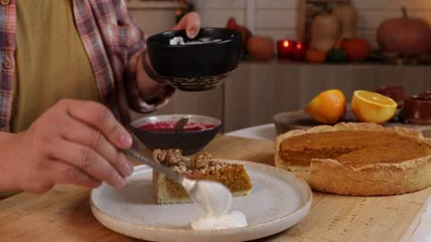 A man decorates a pumpkin pie with whipped cream and pecans Stock Footage 286140295
