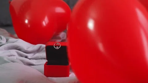 A man decorates the room for a proposal, surrounded by red heart-shaped balloons Stock Footage 298184548