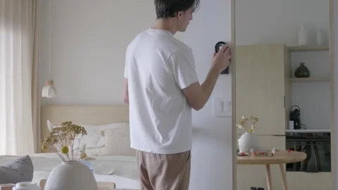 Man Decreasing the Room Temperature with Wall Mounted Smart Thermostat Stock Footage 241378664