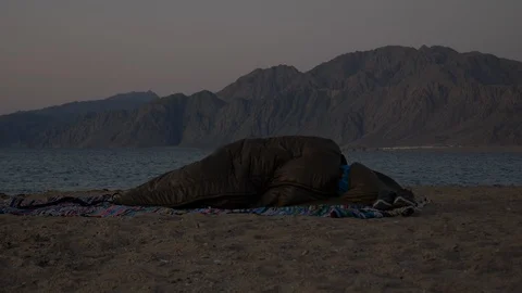 A man in deep sleep in front of the mountain and the sea Stock Footage 97483763
