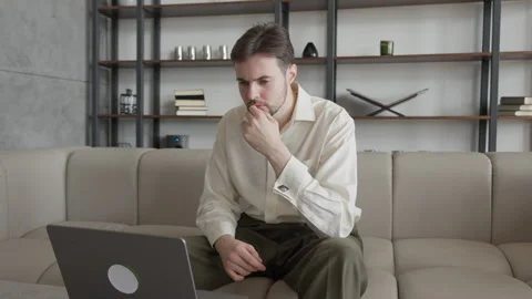 Man Deep In Thought, Looking At Laptop Screen With Focused Expression, Thinking Stock Footage 303085826