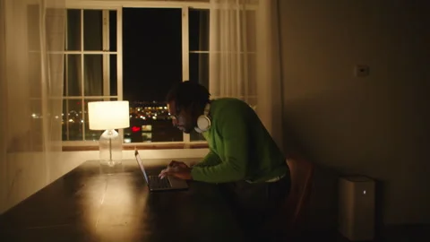 Man deep in thought while typing on laptop in a quiet room at night Stock-Footage 312583571