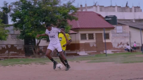Man defends a ball while playing soccer on a bare pitch in Ghana, West Africa Vidéo 253556086