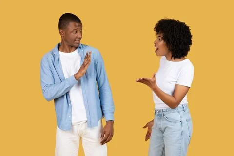 A man defensively gesturing stop with his hand as a woman animatedly talks to Stock Photos