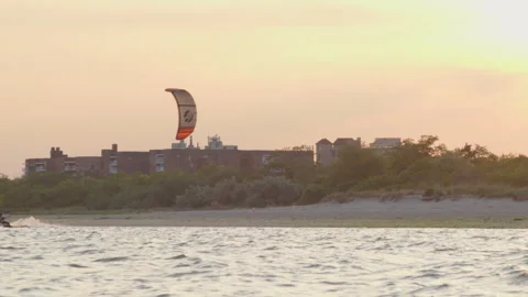 A man deftly glides through the open water under his windsurfing parachute. Video stock 243173166