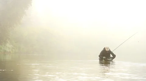 Man Dehooking a Fish in a River Enveloped by Fog Stock Footage 52500625