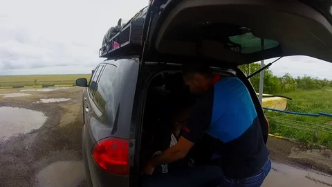 Man delves into a backpack in the trunk of an SUV off the road in the windy Stock Footage 81796669