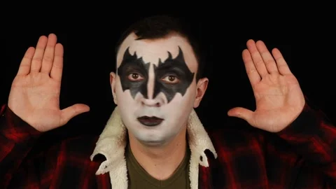 Man in demon makeup standing with raised hands on black background. Stock Footage 146580504