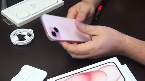 A man demonstrates an iPhone 15. Makes the unpacking of a modern smartphone. Stock Footage 277546317