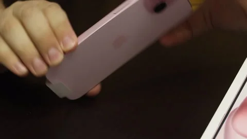 A man demonstrates an iPhone 15. Makes the unpacking of a modern smartphone.. Stock Footage 277546349