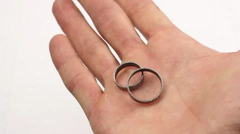 Man demonstrates two silver rings on his palm, then squeezes hand into a fist Stockbeeldmateriaal 57197429