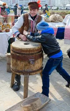 Man demonstrates work of old hand-made mill to boy during Shrovetide Stock Photos
