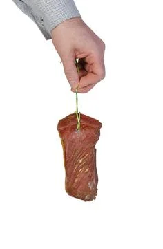 A man is demonstrating appetizing dry-aged meat against a white background. Stock Photos