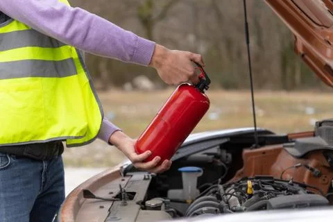 A man demonstrating how to use a fire extinguisher over a car engine Stock Photos