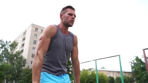 Man is demonstrating L-sit static exercise on parallel bars outdoors Stock-Footage 114089473