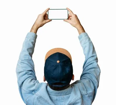 Man in denim jacket and cap holding smartphone above head with raised arms is Stock Photos