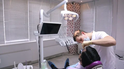 Man dentist makes a first examination of patient lying in chair in dental office Stock Footage 65317941