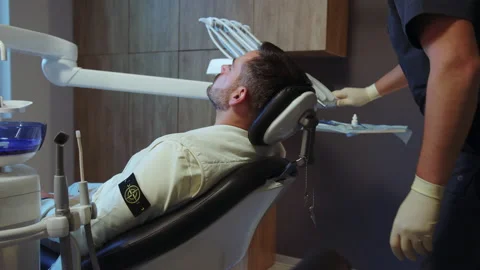 Man dentist preparing patient for the procedure in light dental clinic. Hydience Stock Footage 234613296