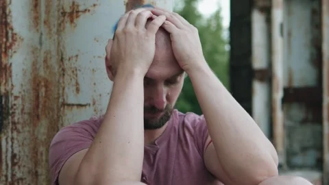 A man in a depressed state sits alone holding his head. Stock Footage 303491361