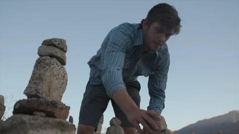 Man on Desert Hike Artfully Stacking Small Rocks with Dog Stock Footage 95932621