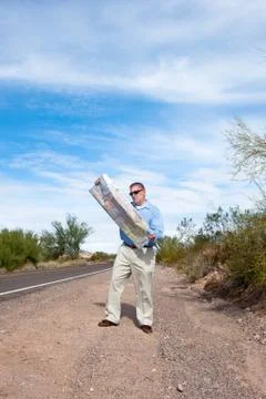 Man on deserted road reading map Stock Photos